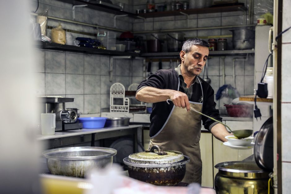 La cocinera sirviendo un guisado de mole en cazuela de barro sobre la plancha de leña