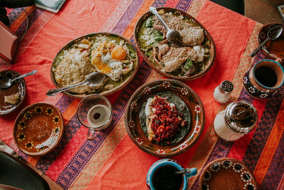 Mesa puesta del restaurante con platos de barro, tortillas y salsas de molcajete